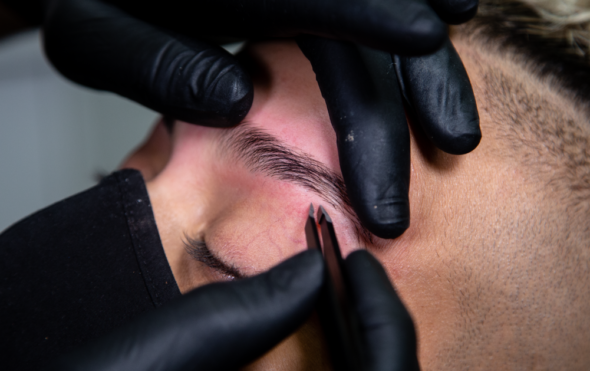 Close up of a brow stylist plucking eyebrows
